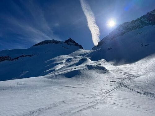 Point de vue sur les montagnes enneigées du Parc Naturel de Posets-Maladeta, Espagne, avec traces de ski après la descente et le Pic Aneto au loin, ascension réalisée lors d'un raid à ski encadré par un guide de haute montagne de Sensations Pyrénées.