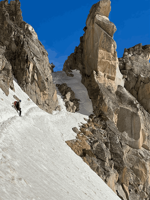 Homme se reposant sur un tracé enneigé avant de gravir une partie de la montagne vers le sommet, ski randonnée en montagne enneigée