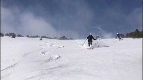 Skieurs traçant des virages serrés dans la poudreuse lors d'une descente dans le Parc des Pyrénées Catalanes, durant un raid à ski, avec un guide de haute montagne.