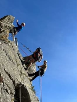 Trois grimpeurs descendant en rappel le long d'une paroi rocheuse.
