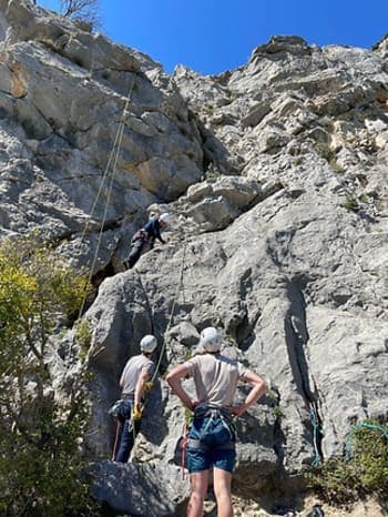 Groupe de grimpeurs équipés de baudriers et casques en train d'escalader une montagne