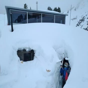 Un skieur rentrant dans un refuge complètement recouvert de neige pour y passer la nuit pendant son raid à ski  à la découverte des Encantats. Un skieur rentrant dans un refuge complètement recouvert de neige pour y passer la nuit pendant son raid à ski  à la découverte des Encantats.